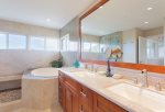 The master bathroom features to vanities, toilet, shower and bath